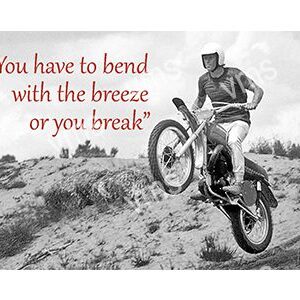A motorcyclist bends forward riding over rough terrain with an inspiring quote.