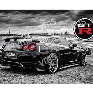 Black Nissan GT-R parked on grass under a cloudy sky.