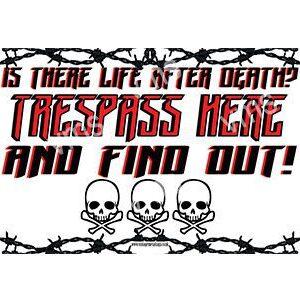 Warning sign with skulls and barbed wire threatening trespassers.