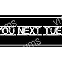 Black and white sign saying 'YOU NEXT TUE' with some parts unclear.