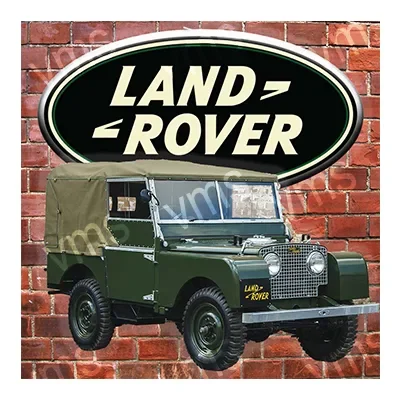 Classic Land Rover vehicle with a green body and canvas roof against a brick wall.