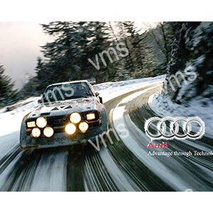 Classic Audi rally car speeding through snowy mountain road.
