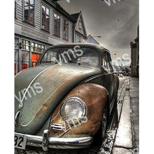 Vintage car parked on a narrow cobblestone street under a cloudy sky.