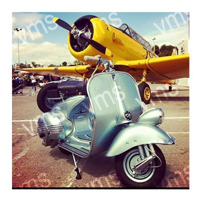 Vintage scooter parked in front of a yellow propeller airplane.